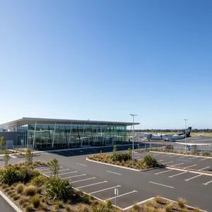 The modern, single-storey terminal building of Hamilton Airport in the Waikato region of New Zealand, viewed from the car park on a sunny day.